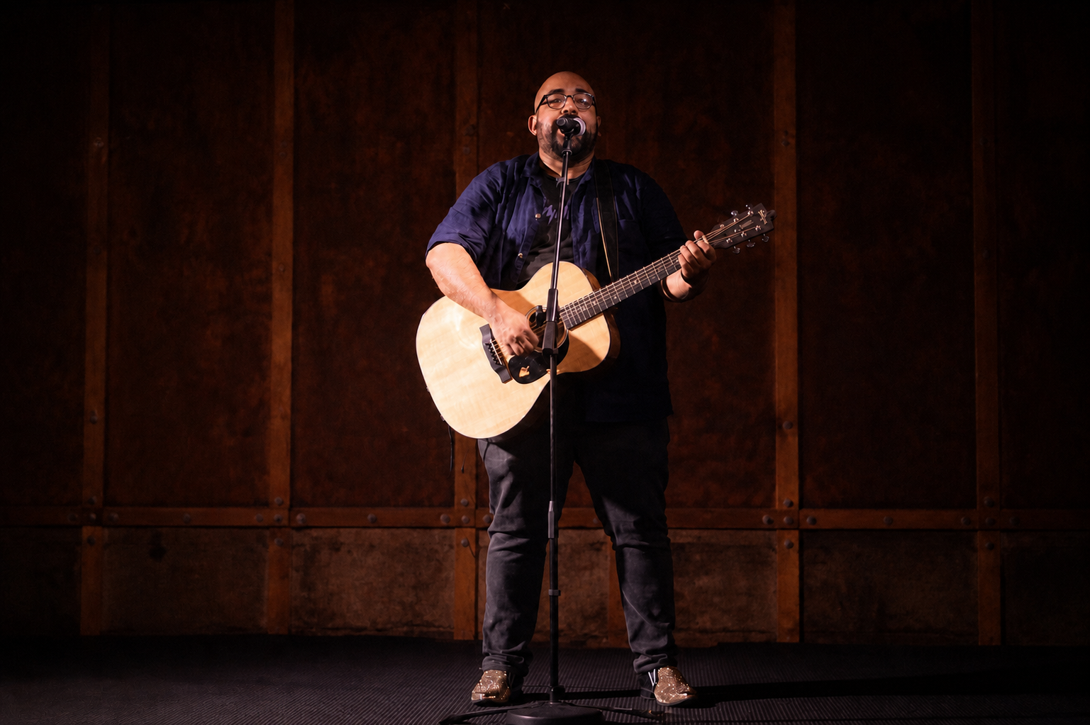 Joshua Jacob singing and playing acoustic guitar on stage